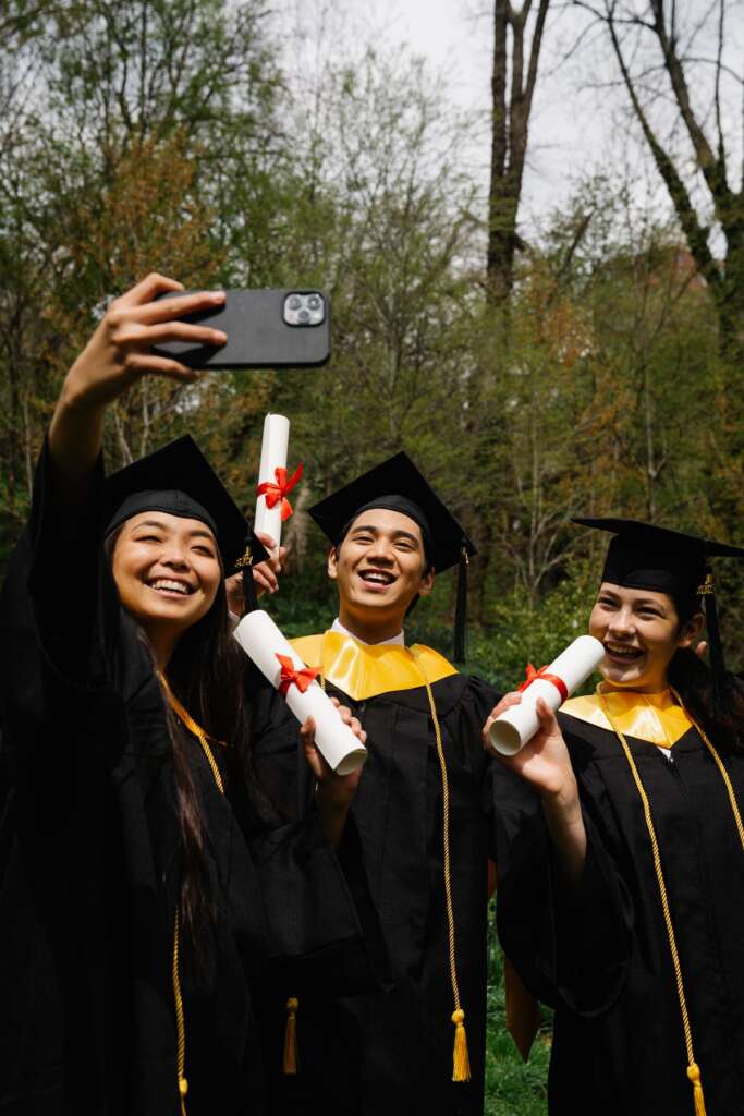 Graduates laughing and holding their diplomas