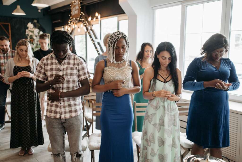 Prayer circle holding hands in a bright room