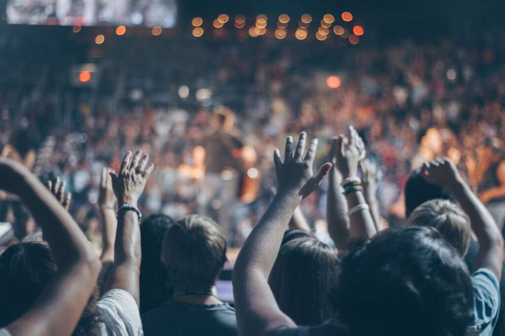 Crowd cheering with raised hands at a night event