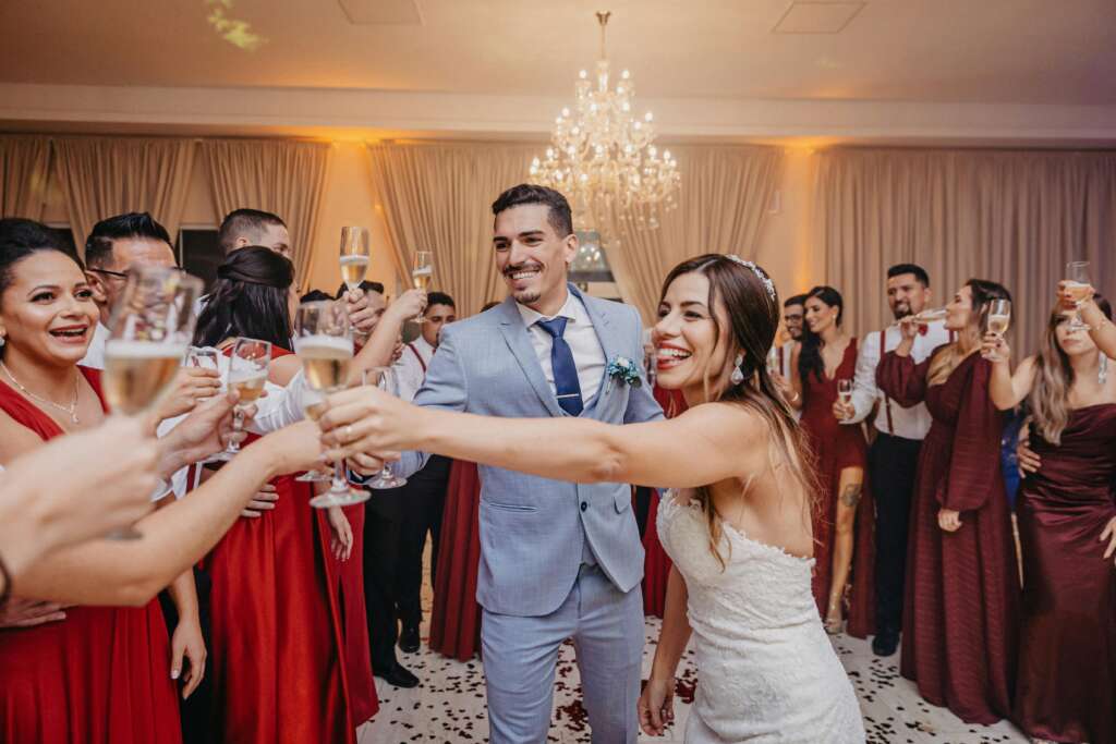 Couple and guests toasting at a wedding reception under a chandelier